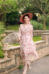 a lady in a pink floral print dress and a straw hat